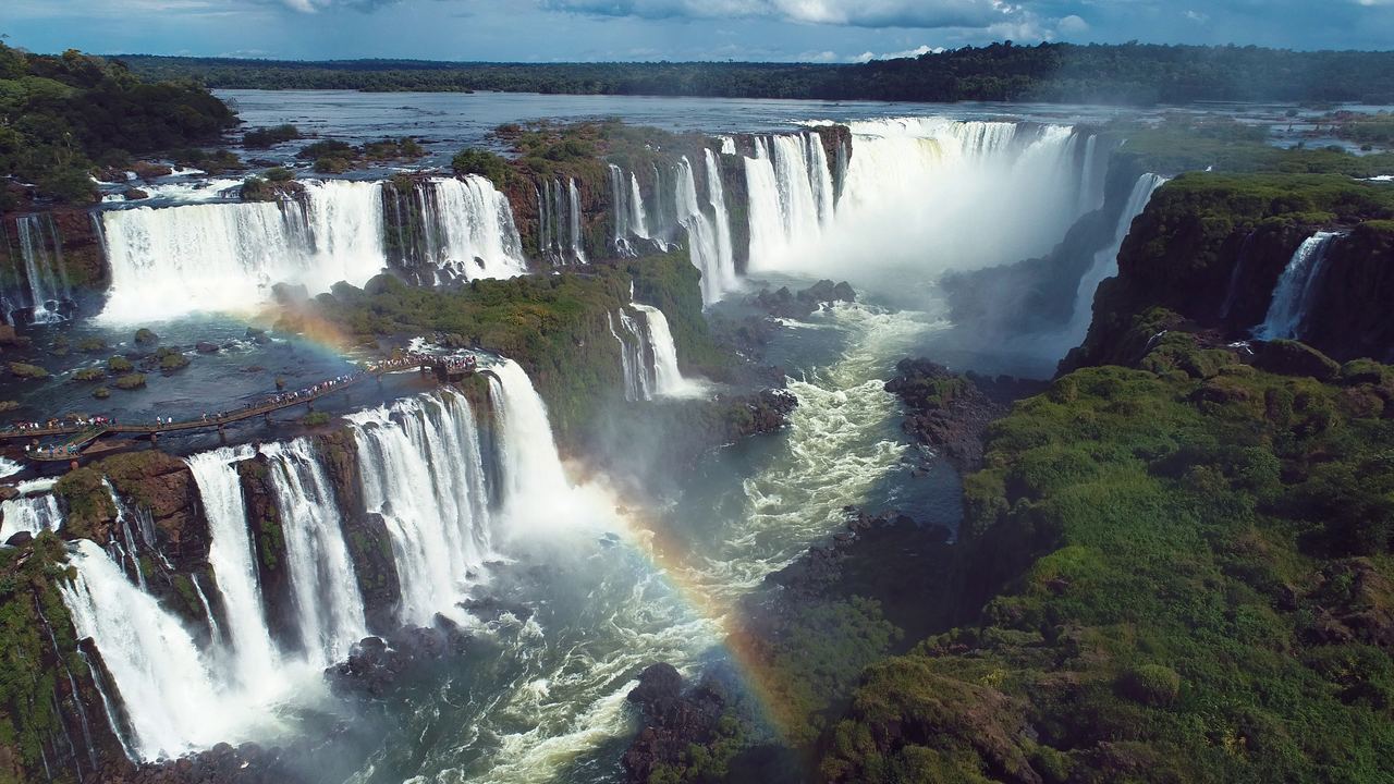 Aerial view of the Iguazu Falls and the walkway along the Brazilian side with a rainbow over the river