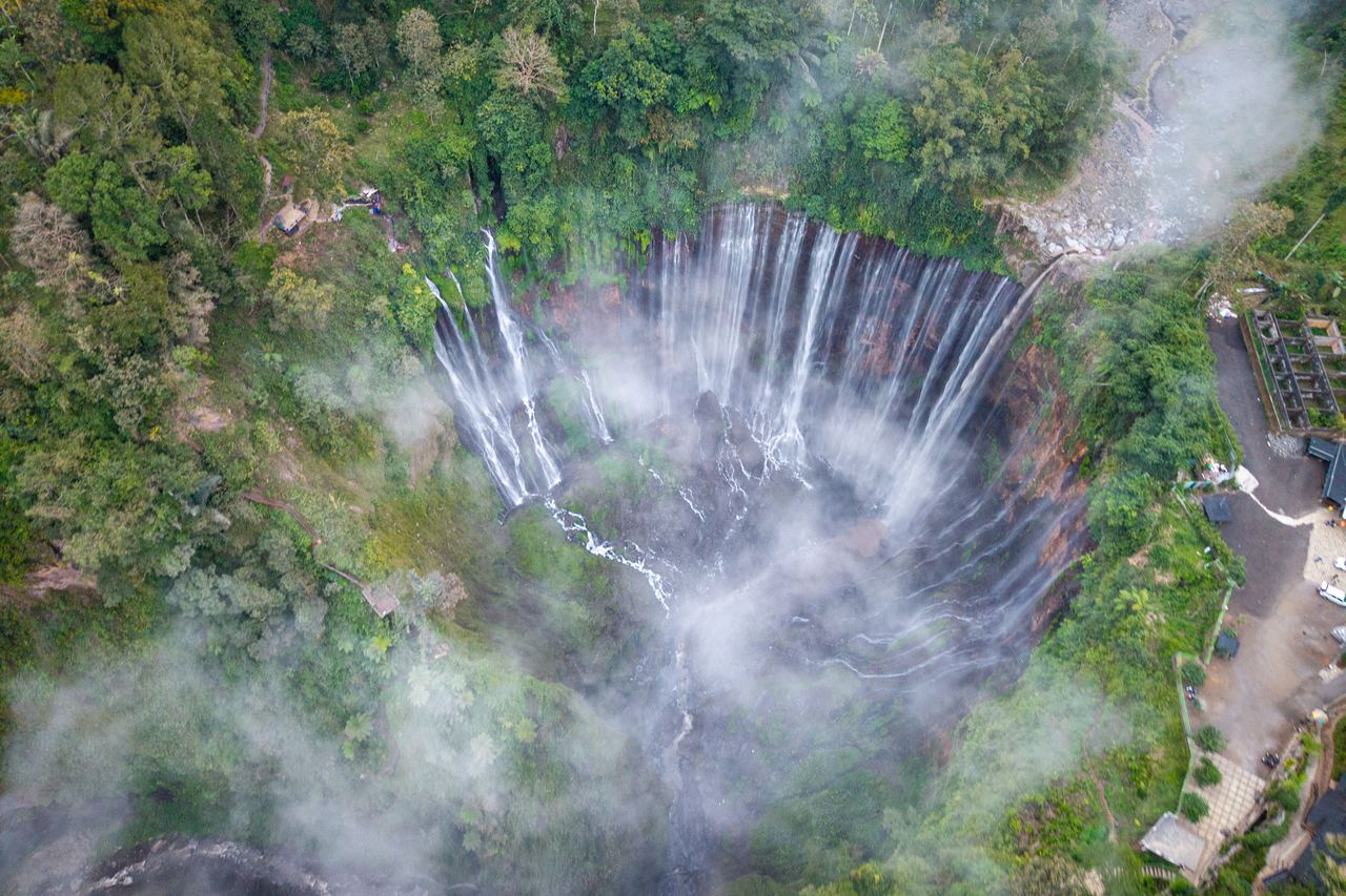 Aerial view of Tumpak Sewu waterfall in East Java, mist rising from the curtain of falls