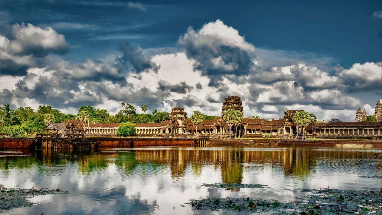 Angkor Wat reflected in a pond under a cloudy blue sky near Siem Reap