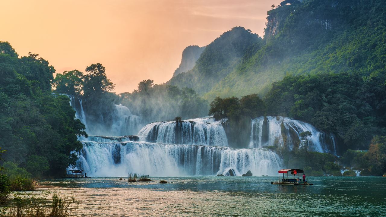 Bamboo raft on the river below Ban Gioc Falls in Cao Bang, with the falls and karst hills behind