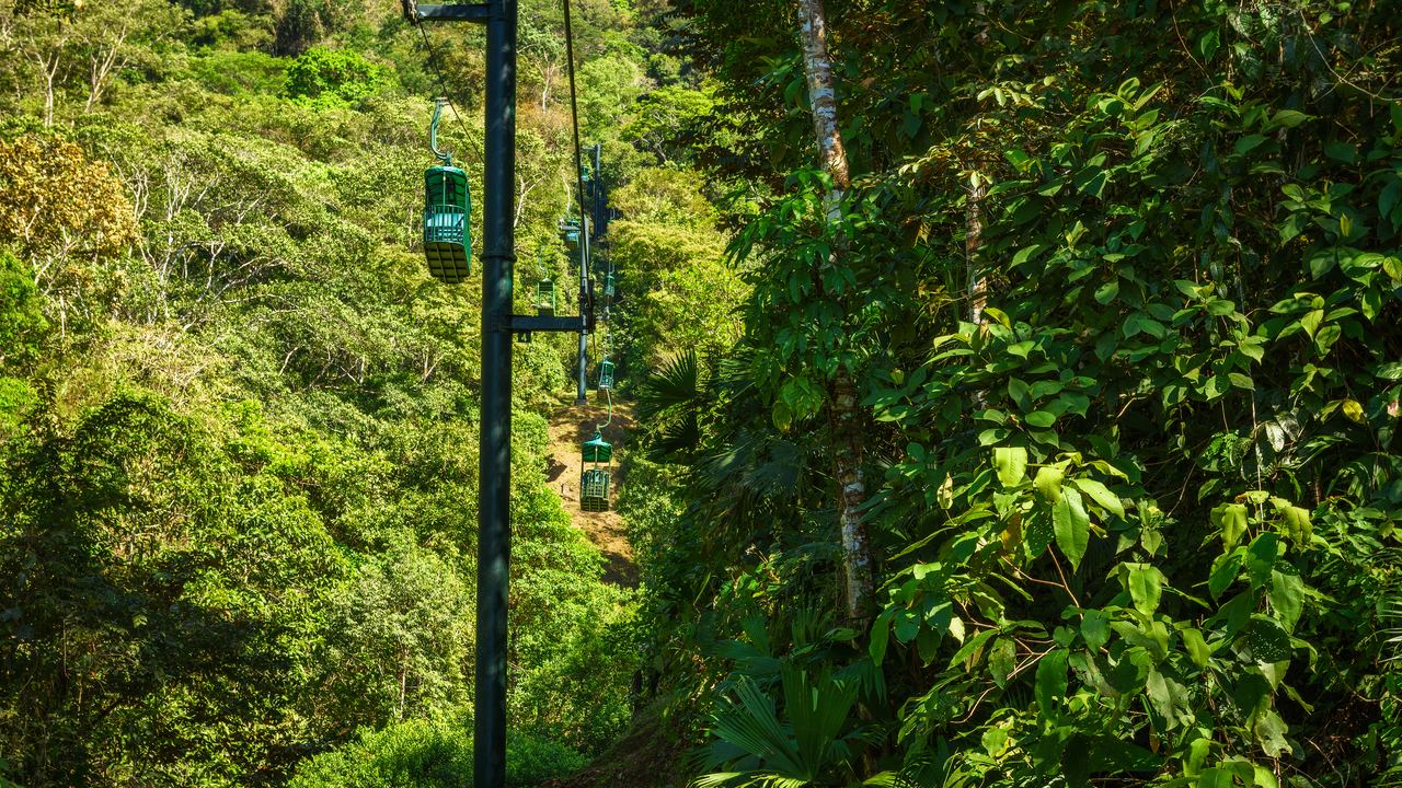 Cable car cabins rising through tropical rainforest in the hills near Jacó, Costa Rica