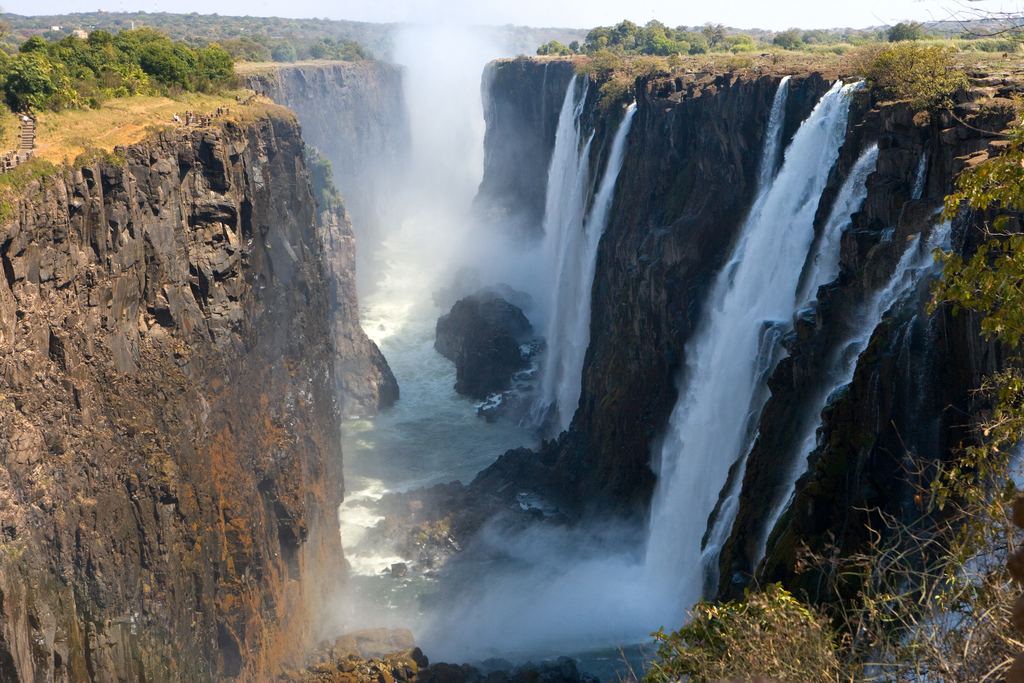 Victoria Falls dropping into a narrow gorge between dark basalt cliffs, with spray rising from the cleft