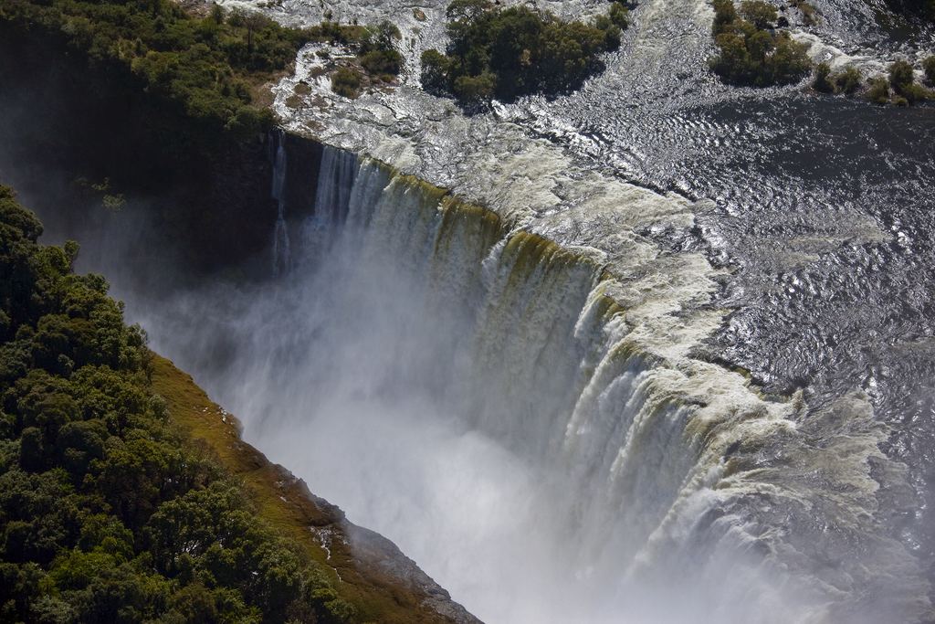 The edge of Victoria Falls seen from above, with spray rising from the gorge below