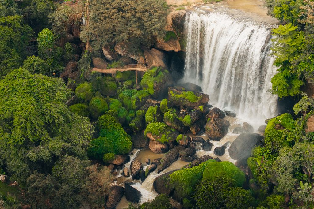 Aerial view of Elephant Falls near Da Lat, a wide sheet of water over mossy rock with a path beside it