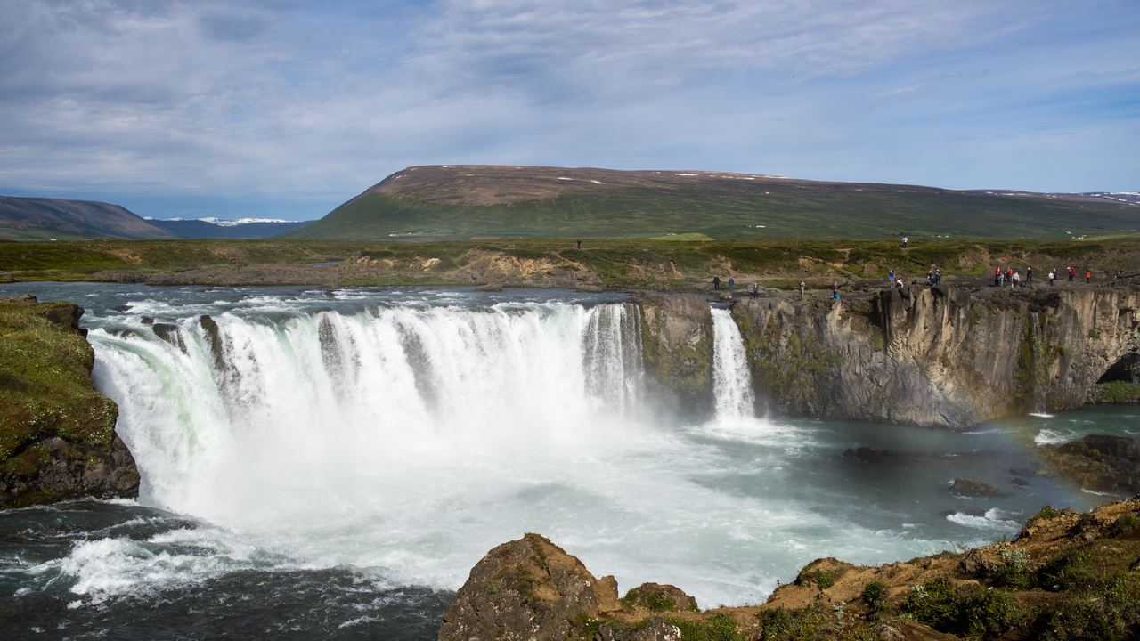 Goðafoss in North Iceland, a wide horseshoe of white water with visitors on the cliff above