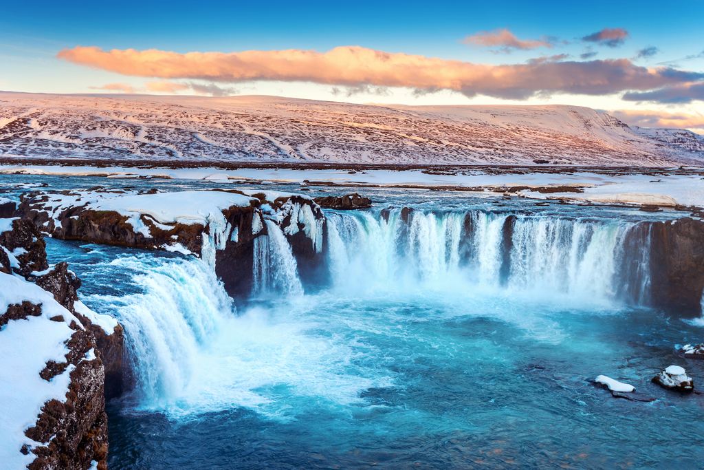 Godafoss in northern Iceland in winter, with snow on the rocks and ice hanging from the cliff edge