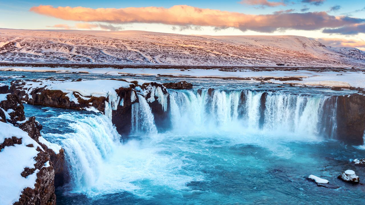 Godafoss in northern Iceland in winter, with snow on the rocks and ice hanging from the cliff edge