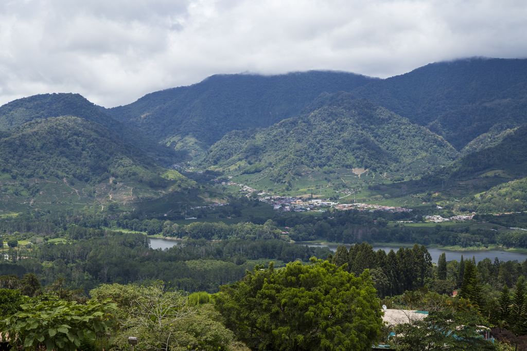 Forested valley with a small town and a lake under cloud-covered mountains in Costa Rica