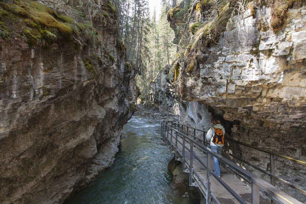 Hiker on the steel walkway along the rock wall of Johnston Canyon, Banff National Park