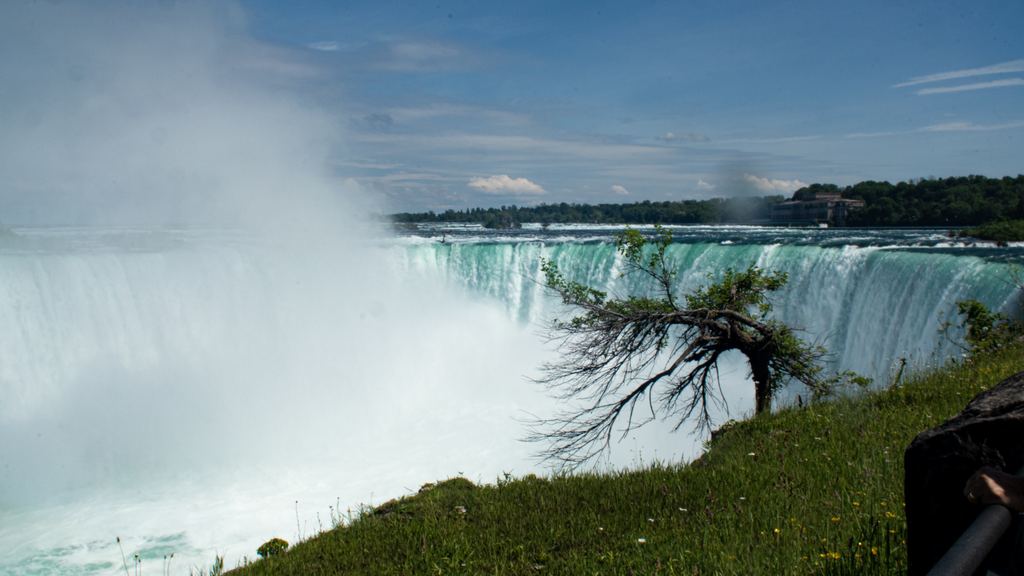 Horseshoe Falls at Niagara on a summer day, seen from the Canadian side with mist rising over the crest