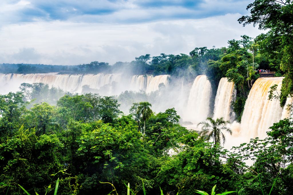 Waterfalls of Iguazu National Park above a forest canopy under a cloudy sky