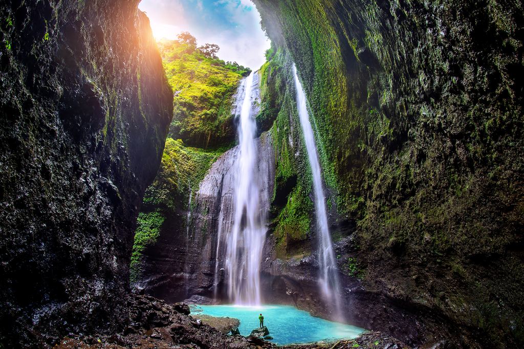 Madakaripura Waterfall dropping into a turquoise pool inside a mossy gorge in East Java