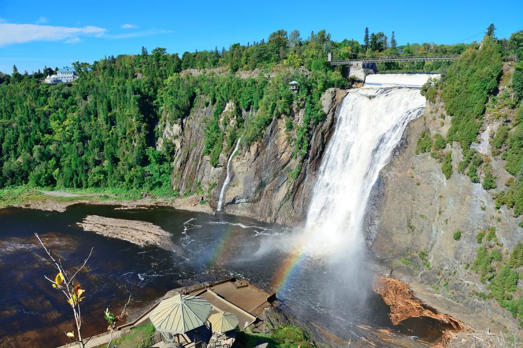 Montmorency Falls near Quebec City in summer, with a rainbow in the spray and a bridge across the top