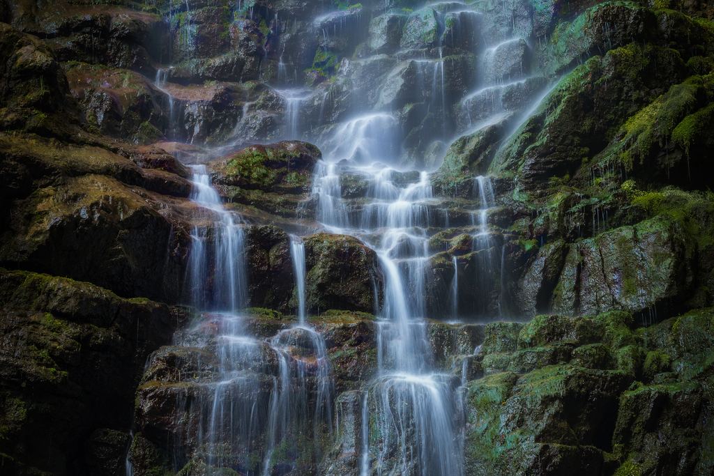 Small waterfall running over dark rock thickly covered with moss in the Skrad municipality, Croatia