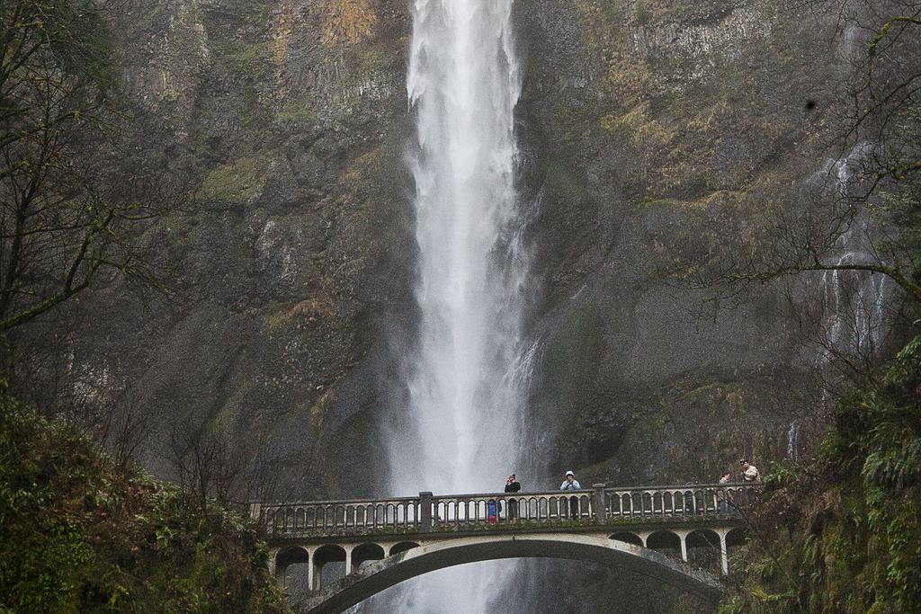Multnomah Falls in fog with the arched Benson Bridge and a few visitors on it, Columbia River Gorge, Oregon