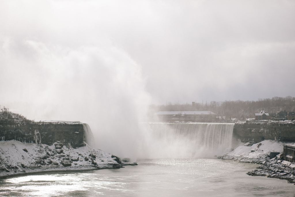 Niagara Falls in winter, with snow on the gorge rim and a cloud of spray rising from the base