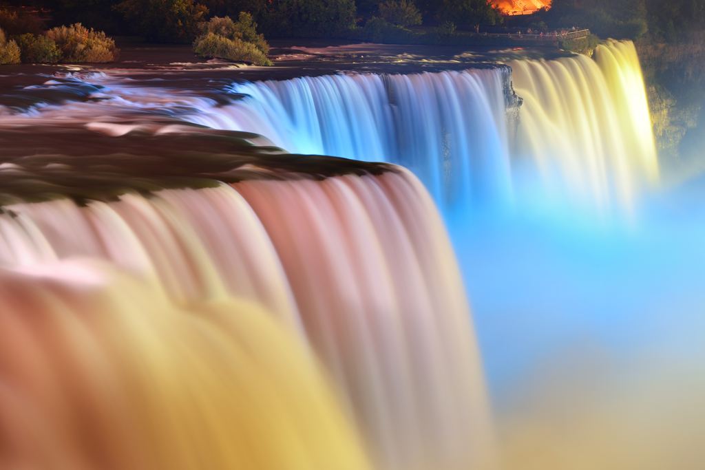 Niagara Falls lit in blue, yellow and pink at night, in a long exposure