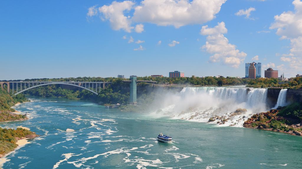 Rainbow Bridge, the American Falls and a tour boat on the green river at Niagara under a blue sky