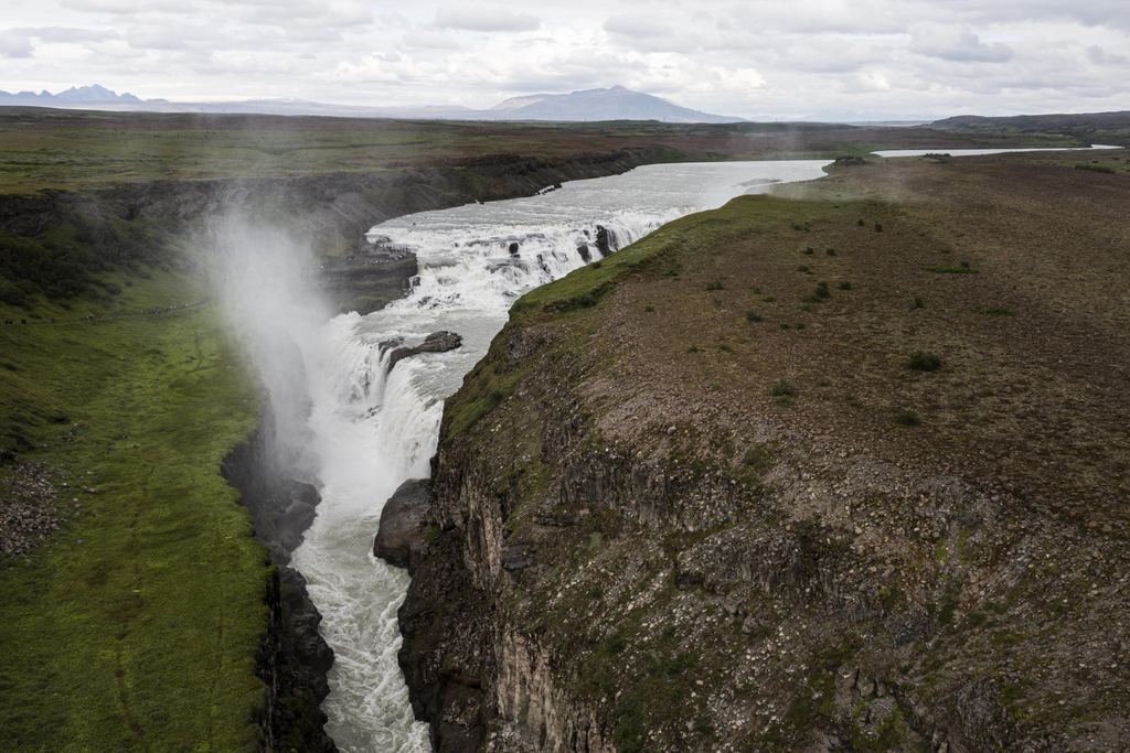 A wide river dropping into a gorge across an open plain in Iceland, seen from above