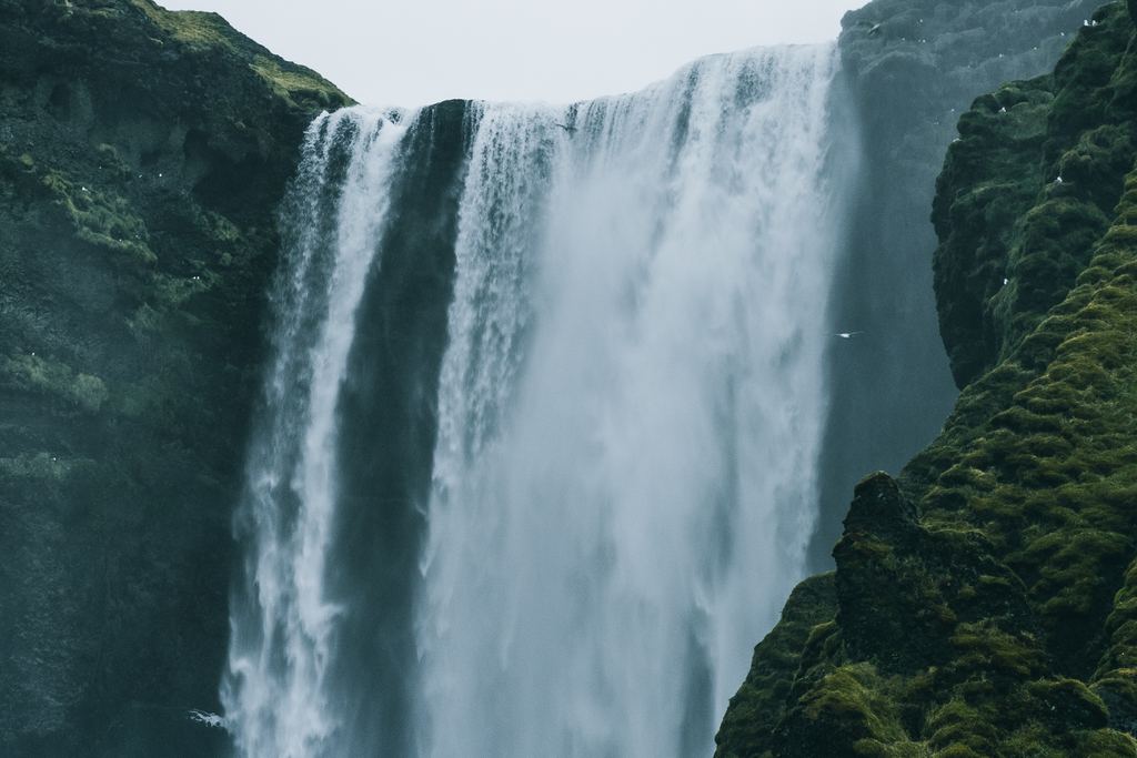 Skogafoss in Iceland on a gloomy day, with green moss on the rocks beside the falling water