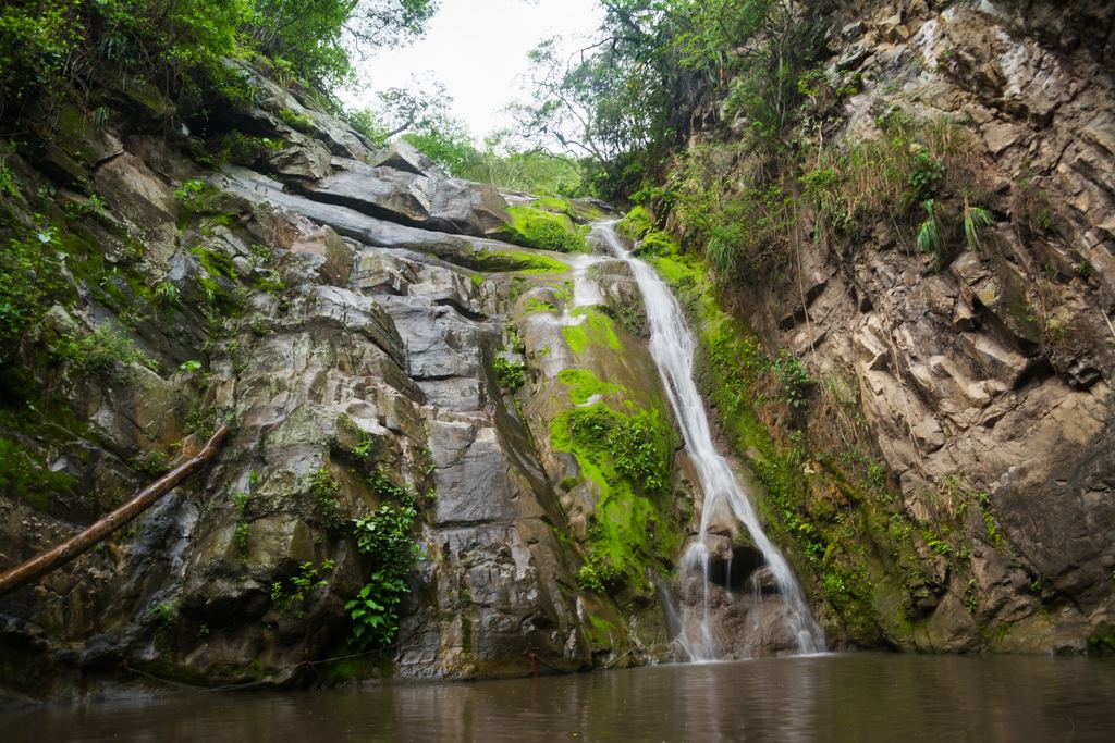 Small waterfall falling down a rocky gorge into a brown pool in Colombia