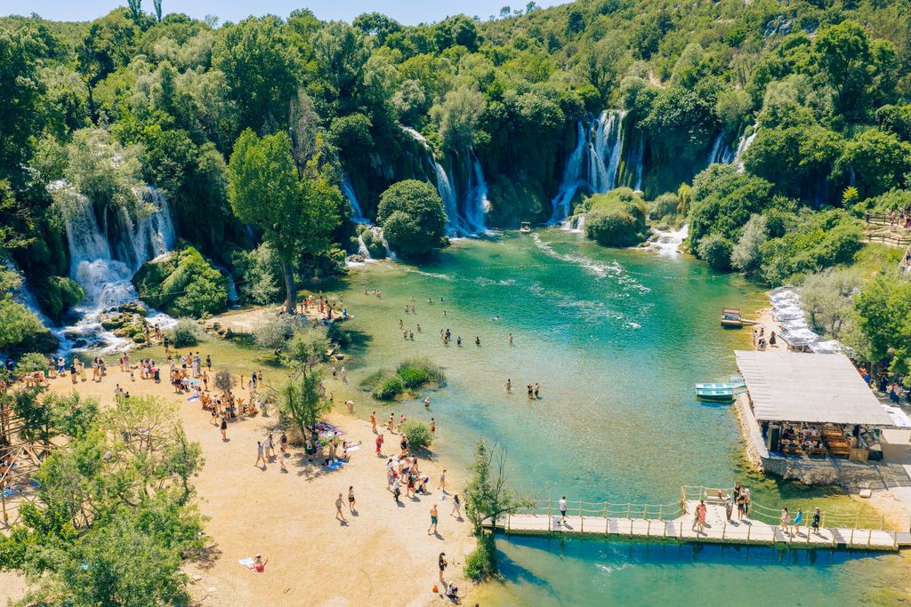 Aerial view of visitors on the beach and in the pool below the Kravica Waterfalls