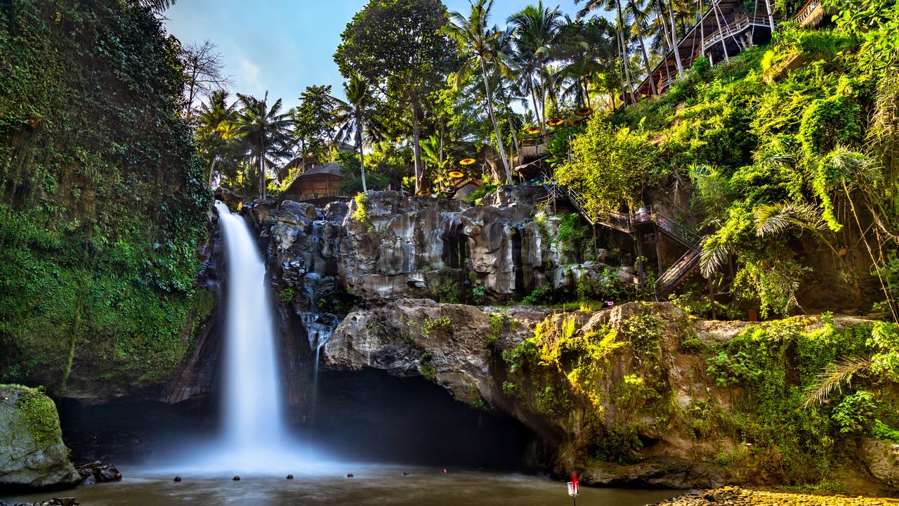 Tegenungan Waterfall near Ubud in Bali, a single drop into a brown pool with palms and forest around