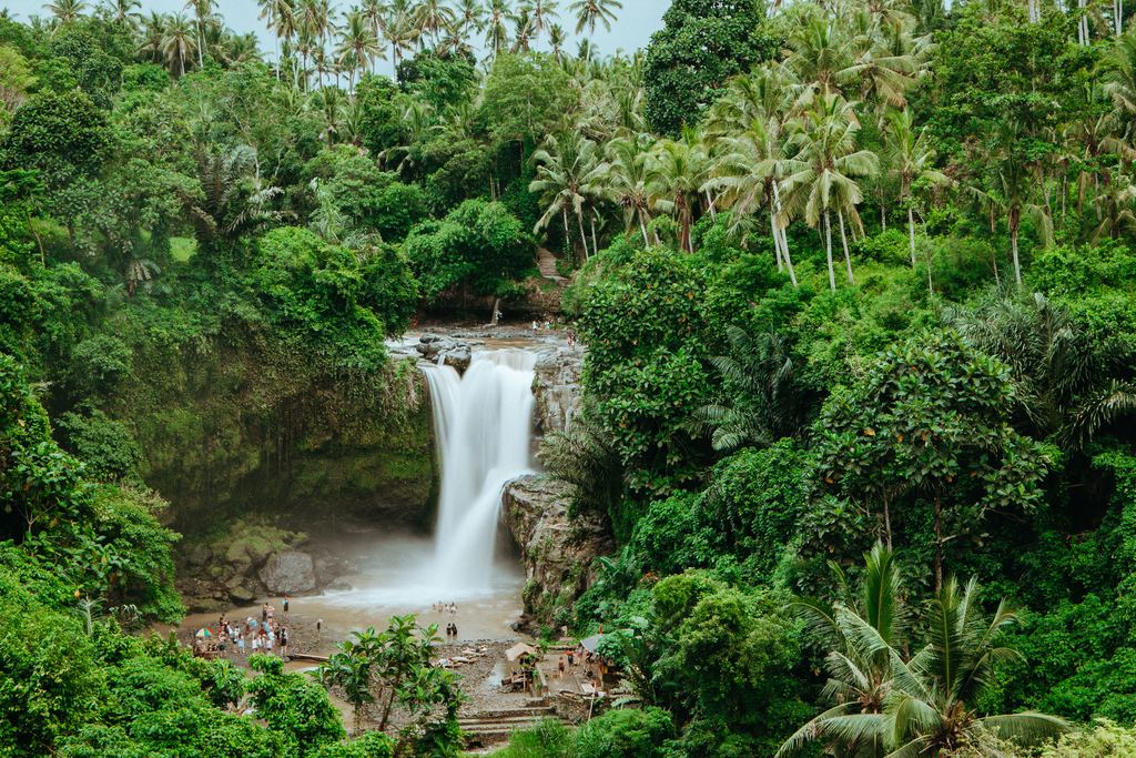 Tegenungan Waterfall near Ubud with visitors at the pool below the fall and forest on both sides