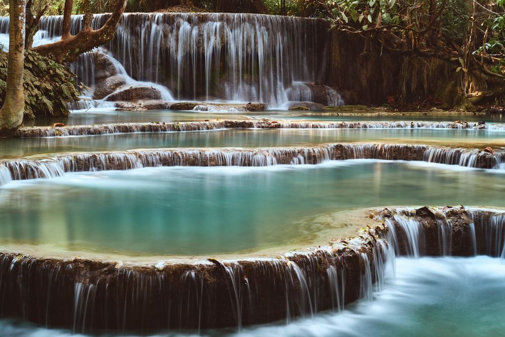 Terraced turquoise pools below a forested waterfall at Kuang Si in Laos