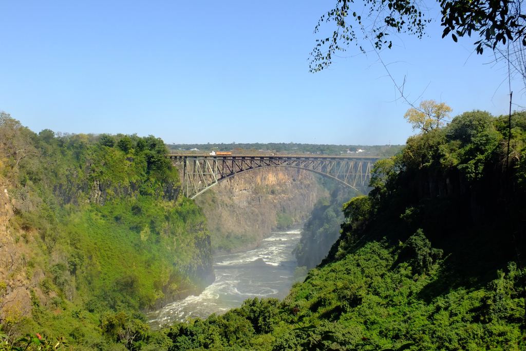 Victoria Falls Bridge seen from the gorge side, a steel arch bridge above green slopes and the river below
