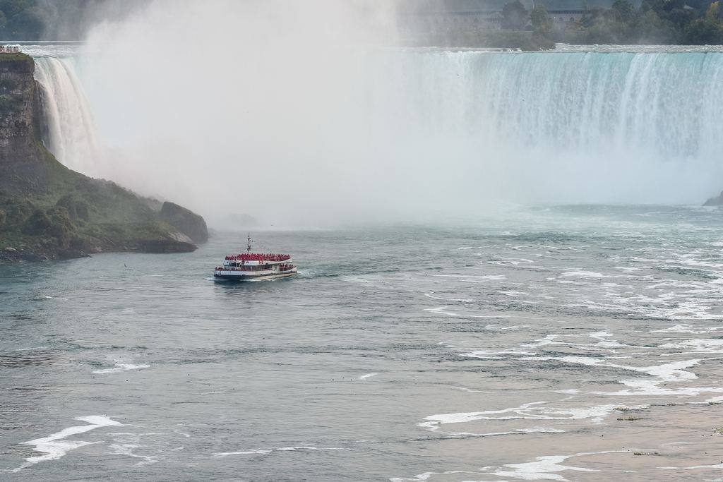 Red and white tour boat with passengers in red ponchos in front of the Horseshoe Falls at Niagara