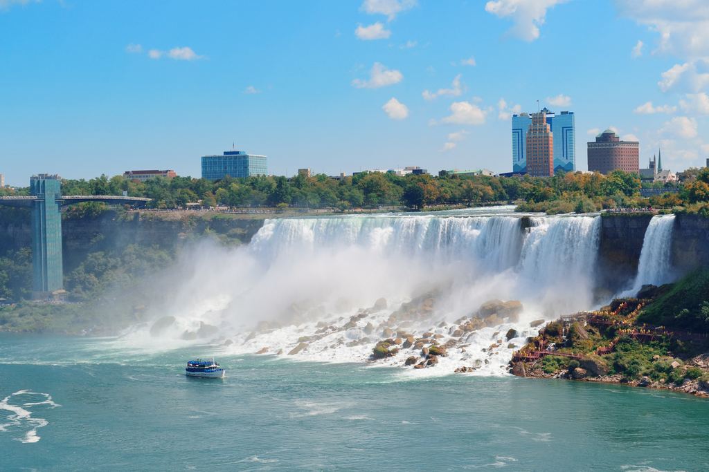 A Maid of the Mist boat in front of the American Falls at Niagara, with rocks at the foot