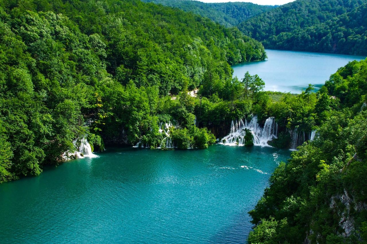 Turquoise lake with small waterfalls at the far shore, seen from above, at Plitvice Lakes National Park, Croatia