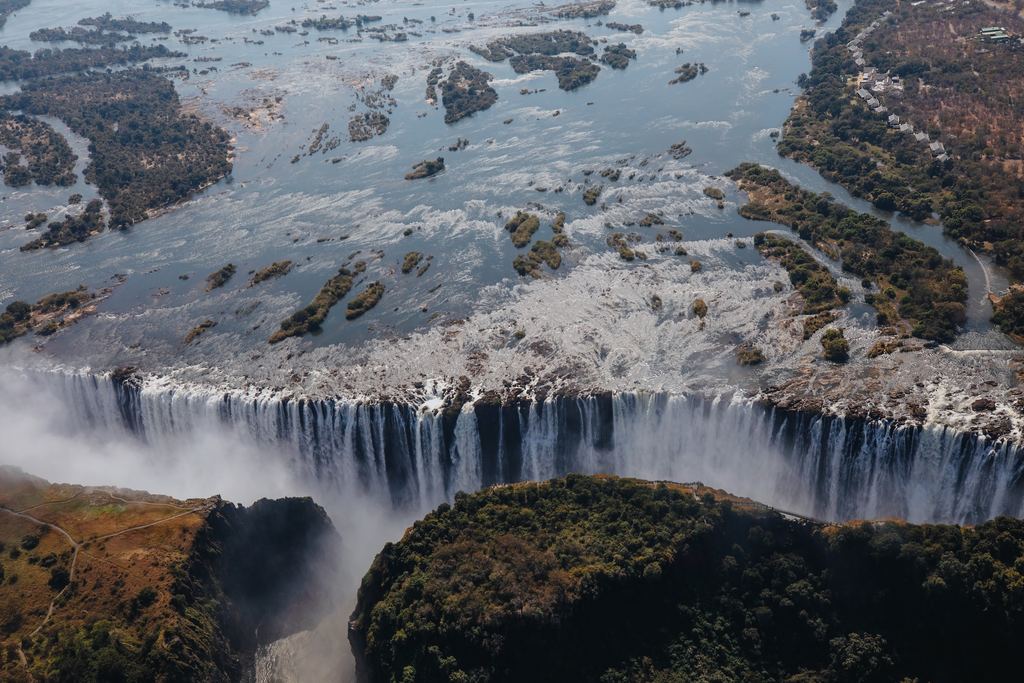 Aerial view of the Zambezi above Victoria Falls, with islands, bare rock and the straight edge of the drop