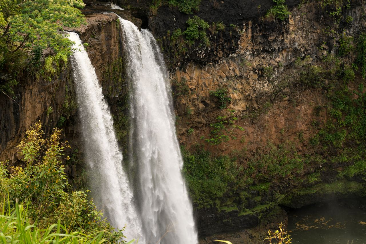 Wailua Falls on Kauai falling in two streams over a rock ledge into a pool
