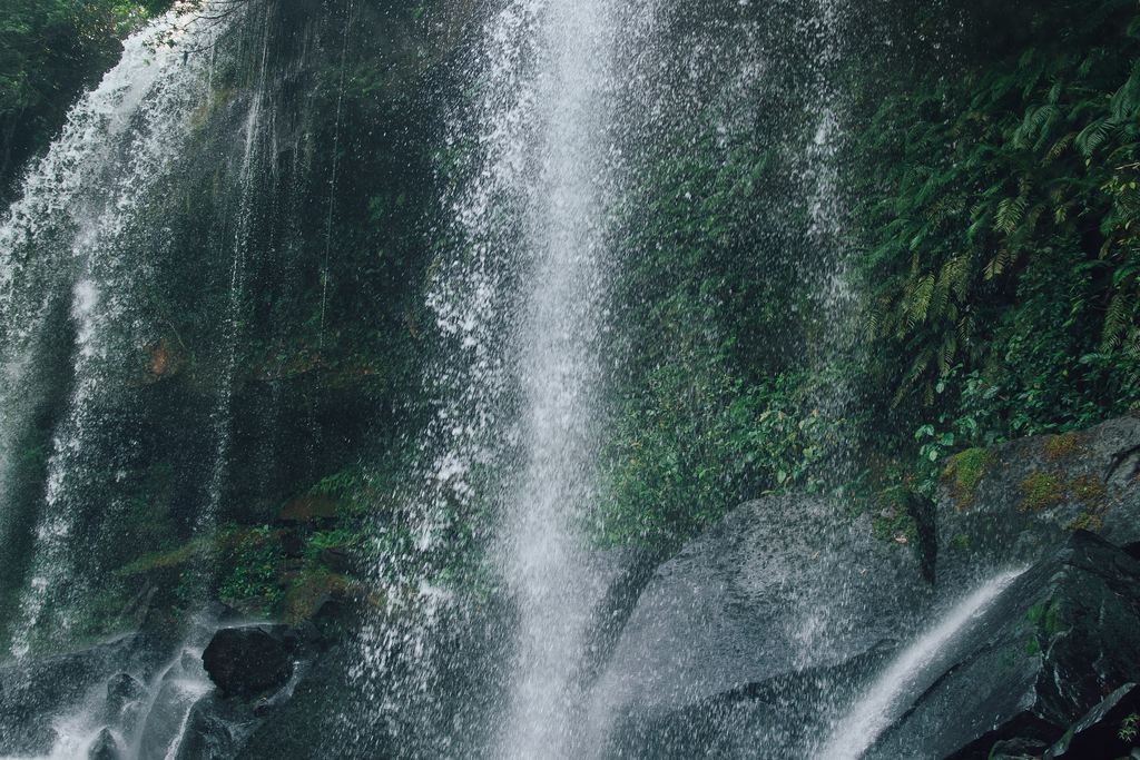 Water falling over dark rocks into a pool at the Phnom Kulen waterfall