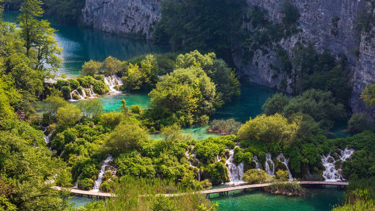 Small waterfalls between turquoise lakes with a wooden boardwalk in Plitvice Lakes National Park, Croatia